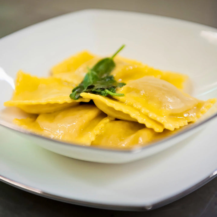 Fresh egg pasta Ravioli di Ricotta e spinaci with creamy ricotta and spinach filling, traditional Italian dish